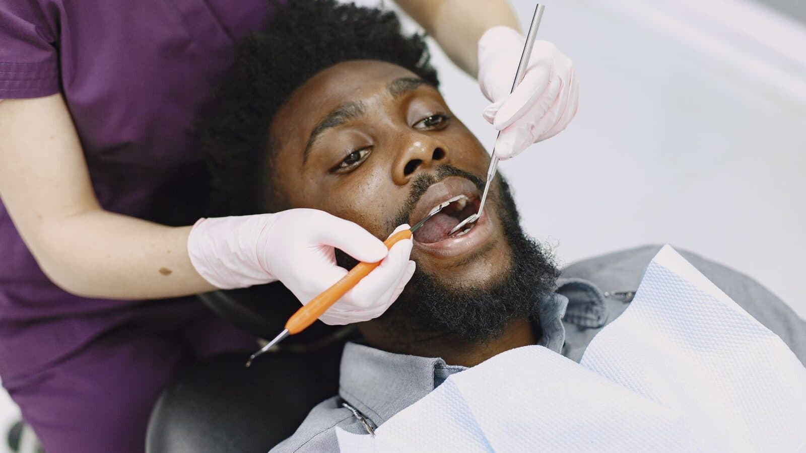 Dentist examining a man's teeth during a routine dental checkup.