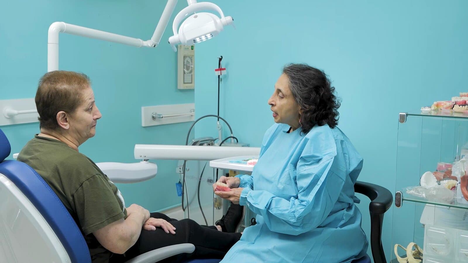 Dr. Raju explaining treatment options with a denture model
